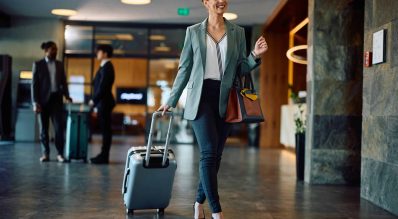 Happy businesswoman with travel bag arriving at the hotel.
